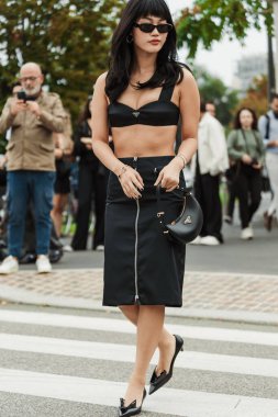 Misafir güneş gözlüğü, bilezik, siyah bir Prada sutyen, siyah bir Prada ön etek, siyah bir Prada çanta, siyah Prada noktalı topuklu ayakkabılar giyer, Milan Moda Haftası Kadın giyim / Yaz 2024 'te PRADA gösterisinin dışında görülürler..