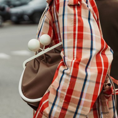 Milan Moda Haftası Kadın giyim / Yaz 2024 'te PRADA gösterisinin dışında kareli trençkot, kravat ve kahverengi çanta giyen bir konuk görüldü..