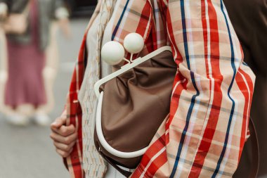 Milan Moda Haftası Kadın giyim / Yaz 2024 'te PRADA gösterisinin dışında kareli trençkot, kravat ve kahverengi çanta giyen bir konuk görüldü..