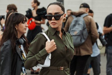 Evangelie Smyrniotaki, Milan Moda Haftası Kadın Giyim / Yaz 2024 'te PRADA gösterisinin dışında görülen siyah güneş gözlüğü, altın küpeler, yeşil düğmeli elbise giyiyor.