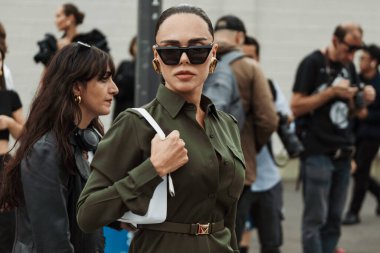Evangelie Smyrniotaki, Milan Moda Haftası Kadın Giyim / Yaz 2024 'te PRADA gösterisinin dışında görülen siyah güneş gözlüğü, altın küpeler, yeşil düğmeli elbise giyiyor.