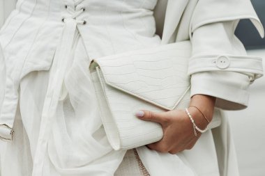 Beyaz elbise, palto ve çanta giyen bir konuk, Milan Moda Haftası Kadın Giyim / Yaz 2024 boyunca PRADA gösterisinin dışında görüldü..