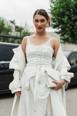 Beyaz elbise, palto ve çanta giyen bir konuk, Milan Moda Haftası Kadın Giyim / Yaz 2024 boyunca PRADA gösterisinin dışında görüldü..