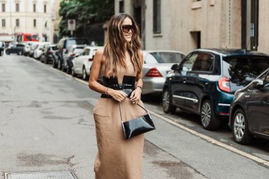 Tamara Kalinic kahverengi güneş gözlüğü, altın bir Cartier kolyesi, vinil siyah bir çanta, vinil siyah kuşak ve uzun bir bej elbise giyerek Milan Moda Haftası Kadın giyim / Yaz 2024 'te MAX MARA gösterisinin dışında görüldü..