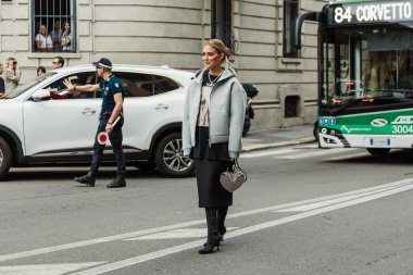 Emili Sindlev küpe, piercing, Chanel inci kolye, kahverengi desenli MaxMara siyah ve bej bir bluz, Miu Miu beyaz kapüşonlu ceket, ince beyaz çizmeli siyah düz bir etek, siyah süet çizmeler, parlak gümüş bir kalp şeklinde çanta,