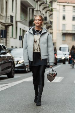 Emili Sindlev küpe, piercing, Chanel inci kolye, kahverengi desenli MaxMara siyah ve bej bir bluz, Miu Miu beyaz kapüşonlu ceket, ince beyaz çizmeli siyah düz bir etek, siyah süet çizmeler, parlak gümüş bir kalp şeklinde çanta,