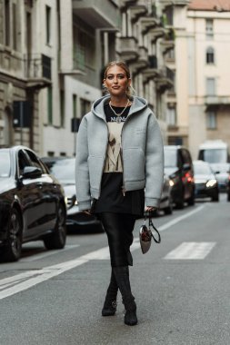 Emili Sindlev küpe, piercing, Chanel inci kolye, kahverengi desenli MaxMara siyah ve bej bir bluz, Miu Miu beyaz kapüşonlu ceket, ince beyaz çizmeli siyah düz bir etek, siyah süet çizmeler, parlak gümüş bir kalp şeklinde çanta,