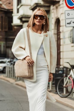 Viktoria Rader Milan Moda Haftası Kadın giyim / Yaz 2024 'te MAX MARA gösterisinin dışında beyaz ceket, elbise, bej çanta, beyaz topuklu ayakkabı giyer..