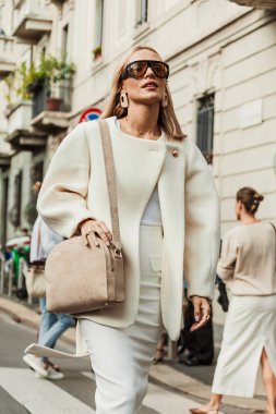 Viktoria Rader Milan Moda Haftası Kadın giyim / Yaz 2024 'te MAX MARA gösterisinin dışında beyaz ceket, elbise, bej çanta, beyaz topuklu ayakkabı giyer..