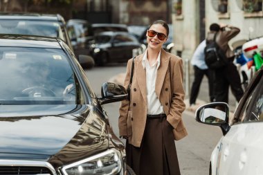 Misafir kırmızı gözlük, beyaz bluz, bej ceket, kahverengi etek, sandalet giyer, Milan Moda Haftası Kadın giyim / Yaz 2024 'te MAX MARA gösterisinin dışında görülmektedir..