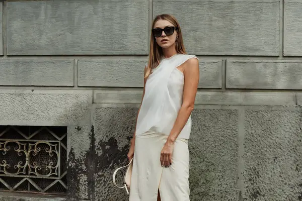 stock image A guest wears sunglasses, white blouse, skirt and bag, seen outside MAX MARA show during Milan Fashion Week Womenswear Spring/Summer 2024.