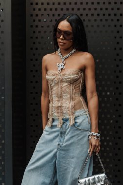 Aleali May güneş gözlüğü, zincirli kolye, fırfırlı omuz üstü, açık mavi geniş kot pantolon ve Milan Moda Haftası Kadın giyim / Yaz 2024 'te Gucci gösterisinin dışında gümüş bir Gucci çanta takıyor..