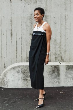 Tamu McPherson Milan Moda Haftası Kadın Giyim / Yaz 2024 'te Sportmax Show' un önünde beyaz, uzun siyah askısız bir elbise giyiyor..