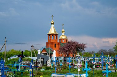ONISHKI, UKRAINE - MAY 4, 2022: Red church on cemetery in Onishki, Ukraine on May 4, 2022.