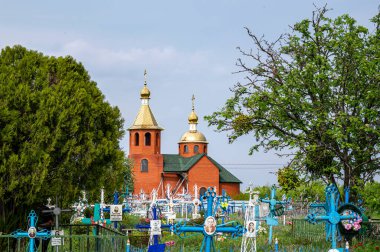 ONISHKI, UKRAINE - MAY 4, 2022: Red church on cemetery in Onishki, Ukraine on May 4, 2022.
