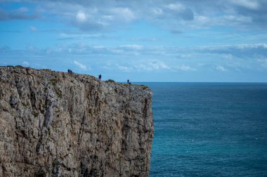 Kayalık uçurum kıyıları ve dalgaların üzerine çöktüğü cennet manzarası. Sagres yakınlarındaki kayalar. Portekiz 'in güneyindeki Algarve bölgesinin Batı Atlantik kıyıları.