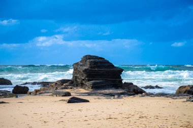 Kayalık uçurum kıyıları ve dalgaların üzerine çöktüğü cennet manzarası. Sörfçü Praia do Castelejo 'daki kayalar Sagres yakınlarında. Portekiz 'in güneyindeki Algarve bölgesinin Batı Atlantik kıyıları.