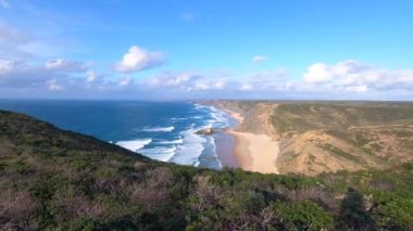 Kayalık uçurum kıyıları ve dalgaların üzerine çöktüğü cennet manzarası. Sörfçü Praia do Castelejo 'daki kayalar Sagres yakınlarında. Portekiz 'in güneyindeki Algarve bölgesinin Batı Atlantik kıyıları.