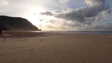 Kayalık uçurum kıyıları ve dalgaların üzerine çöktüğü cennet manzarası. Sörfçü Praia do Castelejo 'daki kayalar Sagres yakınlarında. Portekiz 'in güneyindeki Algarve bölgesinin Batı Atlantik kıyıları.