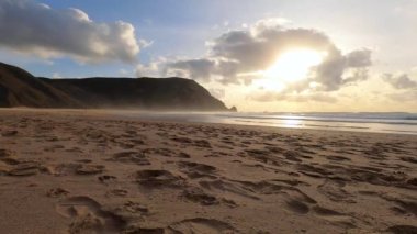 Kayalık uçurum kıyıları ve dalgaların üzerine çöktüğü cennet manzarası. Sörfçü Praia do Castelejo 'daki kayalar Sagres yakınlarında. Portekiz 'in güneyindeki Algarve bölgesinin Batı Atlantik kıyıları.