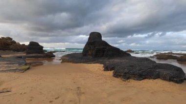 Kayalık uçurum kıyıları ve dalgaların üzerine çöktüğü cennet manzarası. Sörfçü Praia do Castelejo 'daki kayalar Sagres yakınlarında. Portekiz 'in güneyindeki Algarve bölgesinin Batı Atlantik kıyıları.