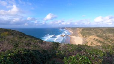 Kayalık uçurum kıyıları ve dalgaların üzerine çöktüğü cennet manzarası. Sörfçü Praia do Castelejo 'daki kayalar Sagres yakınlarında. Portekiz 'in güneyindeki Algarve bölgesinin Batı Atlantik kıyıları.