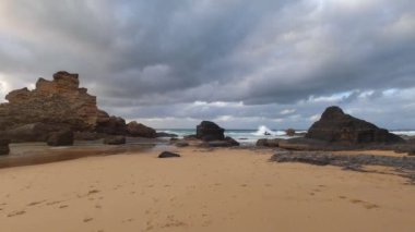 Kayalık uçurum kıyıları ve dalgaların üzerine çöktüğü cennet manzarası. Sörfçü Praia do Castelejo 'daki kayalar Sagres yakınlarında. Portekiz 'in güneyindeki Algarve bölgesinin Batı Atlantik kıyıları.
