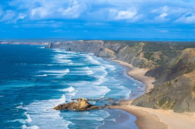 Kayalık uçurum kıyıları ve dalgaların üzerine çöktüğü cennet manzarası. Sagres yakınlarındaki kayalar. Portekiz 'in güneyindeki Algarve bölgesinin Batı Atlantik kıyıları.