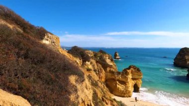 Kayalık uçurum kıyıları ve dalgaların üzerine çöktüğü cennet manzarası. Lagos 'taki Camillo plajı. Portekiz 'in güneyindeki Algarve bölgesinin Batı Atlantik kıyıları.