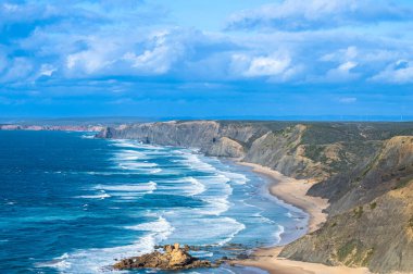 Kayalık uçurum kıyıları ve dalgaların üzerine çöktüğü cennet manzarası. Sagres yakınlarındaki kayalar. Portekiz 'in güneyindeki Algarve bölgesinin Batı Atlantik kıyıları.