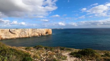 Kayalık uçurum kıyıları ve dalgaların üzerine çöktüğü cennet manzarası. Sörfçü Praia do Castelejo 'daki kayalar Sagres yakınlarında. Portekiz 'in güneyindeki Algarve bölgesinin Batı Atlantik kıyıları.