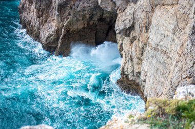 Kayalık uçurum kıyıları ve dalgaların üzerine çöktüğü cennet manzarası. Sagres yakınlarındaki kayalar. Portekiz 'in güneyindeki Algarve bölgesinin Batı Atlantik kıyıları.