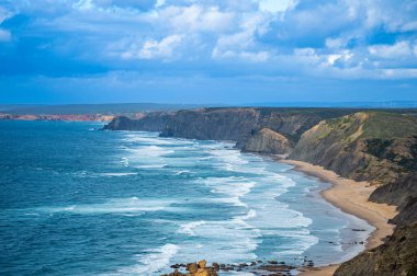 Kayalık uçurum kıyıları ve dalgaların üzerine çöktüğü cennet manzarası. Sagres yakınlarındaki kayalar. Portekiz 'in güneyindeki Algarve bölgesinin Batı Atlantik kıyıları.
