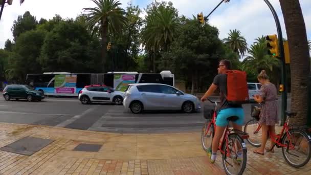 2023年7月17日 スペインのマラガで午前中に港近くのマラガ公園への道を横断するサイクリスト — ストック動画