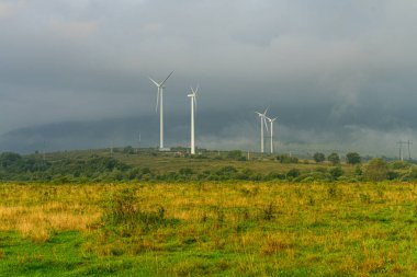 Ukrayna, sisli gündoğumunda kırsal bir alanda yel değirmenleri