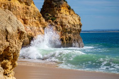 Kayalık uçurum kıyıları ve dalgaların üzerine çöktüğü cennet manzarası. Lagos 'taki Camillo plajı. Portekiz 'in güneyindeki Algarve bölgesinin Batı Atlantik kıyıları.