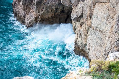 Kayalık uçurum kıyıları ve dalgaların üzerine çöktüğü cennet manzarası. Sagres yakınlarındaki kayalar. Portekiz 'in güneyindeki Algarve bölgesinin Batı Atlantik kıyıları.