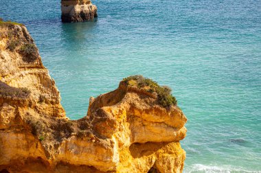 Kayalık uçurum kıyıları ve dalgaların üzerine çöktüğü cennet manzarası. Lagos 'taki Camillo plajı. Portekiz 'in güneyindeki Algarve bölgesinin Batı Atlantik kıyıları.