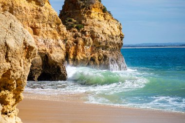 Kayalık uçurum kıyıları ve dalgaların üzerine çöktüğü cennet manzarası. Lagos 'taki Camillo plajı. Portekiz 'in güneyindeki Algarve bölgesinin Batı Atlantik kıyıları.