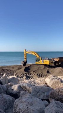 TORREMOLINOS, İspanya - 21 Mayıs 2024: Komatsu kazıcısı 21 Mayıs 2024 tarihinde İspanya 'nın Torremolinos kentindeki kumsaldaki kumu düzleştirir