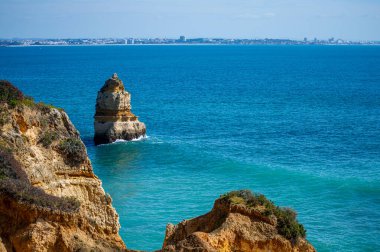 Kayalık uçurum kıyıları ve dalgaların üzerine çöktüğü cennet manzarası. Lagos 'taki Camillo plajı. Portekiz 'in güneyindeki Algarve bölgesinin Batı Atlantik kıyıları.