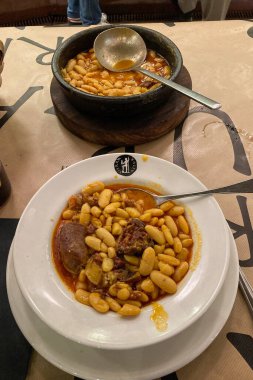 Oviedo, İspanya - 16 Eylül 2024: Fabada Asturiana, tipik bir İspanyol fasulye güveci. 16 Eylül 2024 'te İspanya' nın Oviedo şehrinde lahanalı beyaz fasulyeler