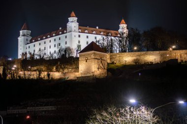 SLOVAKIA, BRATISLAVA - 8 Ocak 2025 Bratislava Kalesi 'nin gece görüşü, Bratislava' daki Küçük Karpatlar 'ın izole edilmiş kayalık tepesinde dört köşeli kuleleri olan devasa dikdörtgen bina