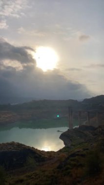 Bulutlu havada baraj gölünün üzerinde gün doğumu, Granada ili, Endülüs, İspanya