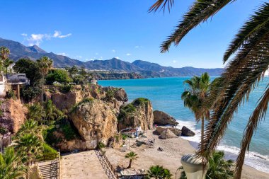 NERJA, İspanya - 22 Mart 2025: Işıldayan deniz ve büyüleyici şehrin muhteşem manzaraları, 22 Mart 2025 tarihinde İspanya 'nın Nerja kentinde nefes kesen kıyı manzaraları ve pitoresk bir atmosfer sunuyor.