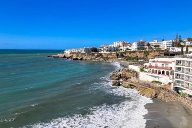 NERJA, İspanya - 22 Mart 2025: Işıldayan deniz ve büyüleyici şehrin muhteşem manzaraları, 22 Mart 2025 tarihinde İspanya 'nın Nerja kentinde nefes kesen kıyı manzaraları ve pitoresk bir atmosfer sunuyor.