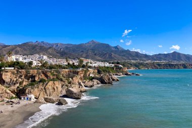 NERJA, İspanya - 22 Mart 2025: Işıldayan deniz ve büyüleyici şehrin muhteşem manzaraları, 22 Mart 2025 tarihinde İspanya 'nın Nerja kentinde nefes kesen kıyı manzaraları ve pitoresk bir atmosfer sunuyor.