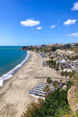 NERJA, İspanya - 22 Mart 2025: Işıldayan deniz ve büyüleyici şehrin muhteşem manzaraları, 22 Mart 2025 tarihinde İspanya 'nın Nerja kentinde nefes kesen kıyı manzaraları ve pitoresk bir atmosfer sunuyor.