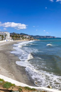 NERJA, İspanya - 22 Mart 2025: Işıldayan deniz ve büyüleyici şehrin muhteşem manzaraları, 22 Mart 2025 tarihinde İspanya 'nın Nerja kentinde nefes kesen kıyı manzaraları ve pitoresk bir atmosfer sunuyor.