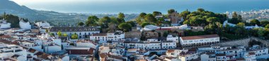 MIJAS, SPAIN - 7 Temmuz 2024: Kosta del Sol 'a tepeden bakan, İspanya' nın Endülüs kentindeki Mijas, Endülüs kentindeki beyaz yıkanmış binalar köyü ile tanınan büyüleyici beyaz İspanyol köyü